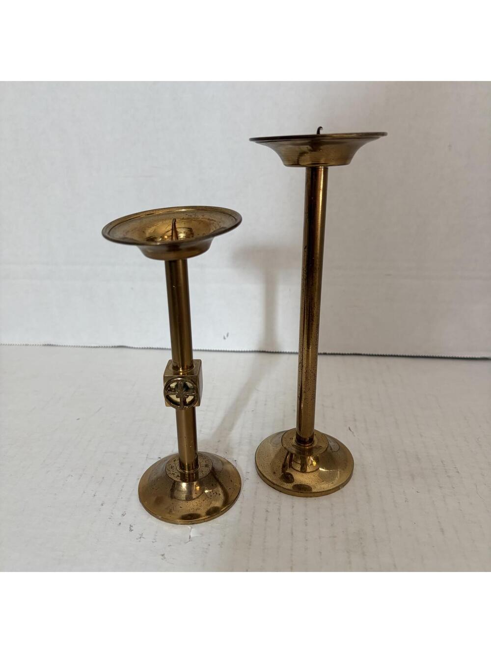 A pair of vintage brass candlesticks, one with a decorative square element.